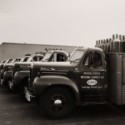 Image of old trucks carrying tanks of gases